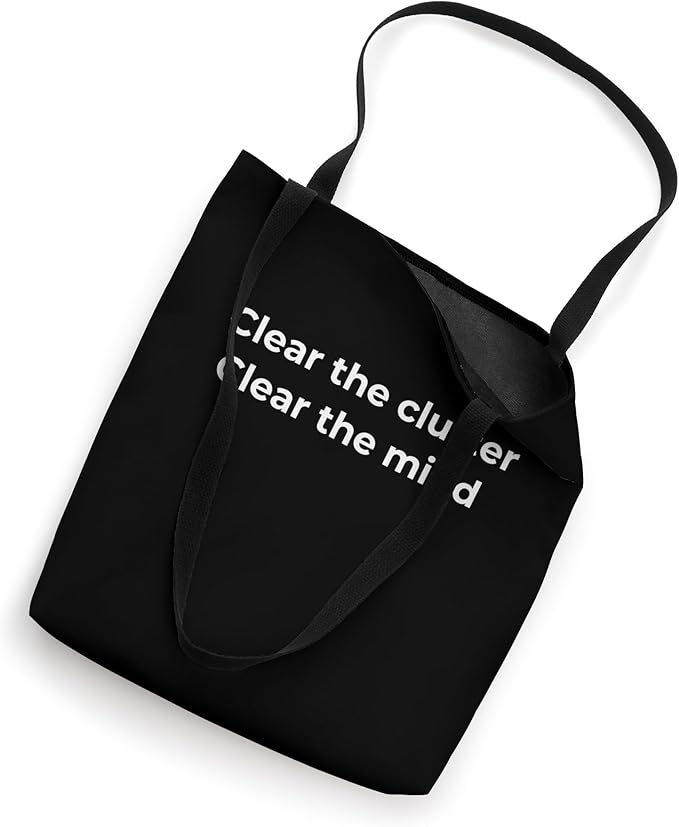 Black reusable tote bag with the minimalist quote "Clear the clutter, clear the mind," promoting a decluttered lifestyle.