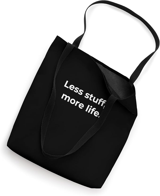 Black reusable tote bag with the minimalist quote "Less stuff, more life," promoting a decluttered and intentional lifestyle.